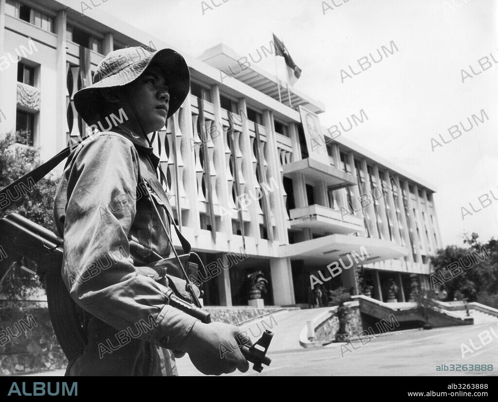 Republic of South Vietnam. Former presidential palace of dictator Nguyen Van Thieu in downtown Saigon now houses the Military Administration Committee of the Saigon-Gia Dinh region. A Ho Chi Minh portrait along with RSV and DRV flags adorn the entrance. A soldier of the liberation forces stands guard. 1975.