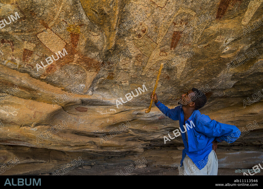 Guide pointing at cave paintings in Lass Geel caves, Somaliland, Somalia, Africa.