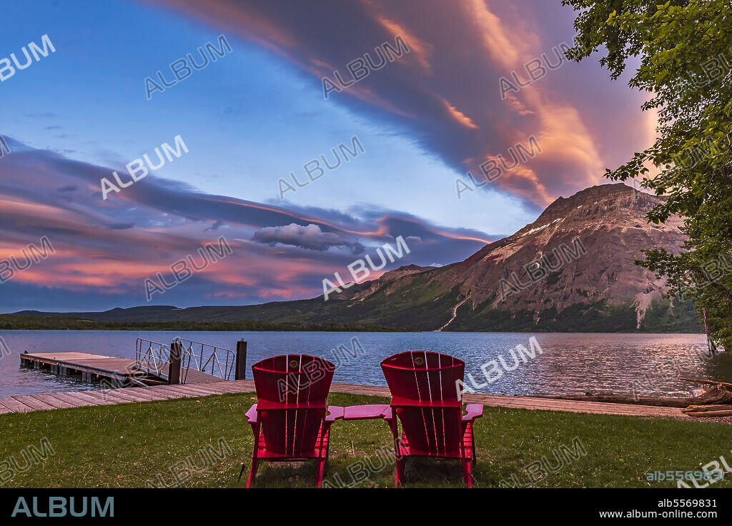 June 17, 2017 - The iconic red chairs of Parks Canada in the sunset light at Middle Waterton Lake in Waterton Lakes National Park, Canada.. Vimy Peak is at right.