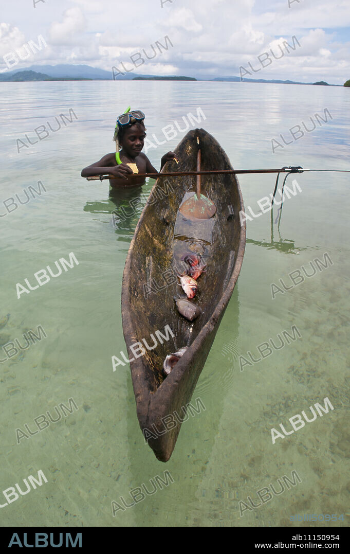 Young boy goes fishing with his canoe and harpoon, Marovo lagoon, Solomon Islands, Pacific.