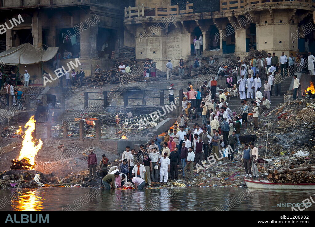 Body bathed in River Ganges and traditional Hindu cremation on funeral pyre at Manikarnika Ghat in Holy City of Varanasi, Benares, India.