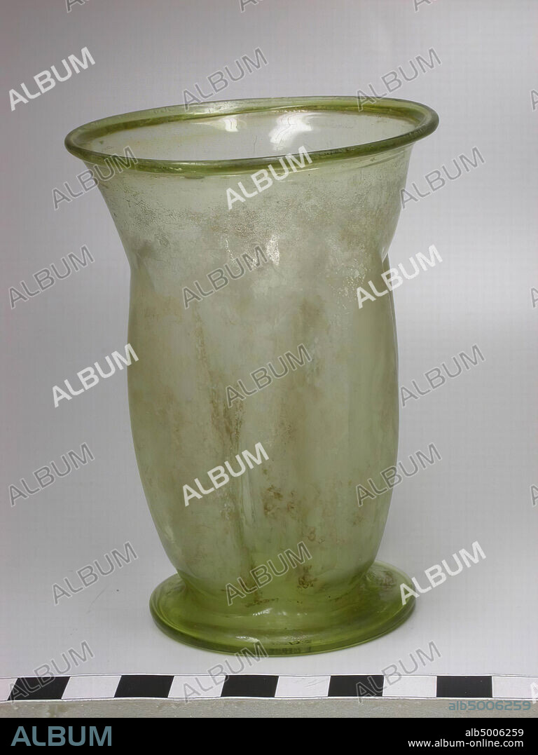 Blown glass beaker with four indentations in the wall. Thin-walled, transparent, almost colorless glass, slightly greenish in thick places. Canting torus edge at the top. Cylinder shaped body, slightly convex. Four dents fold regularly distributed over the surface, running from about 2.5 cm below the top edge to the flat top of the outstanding foot. Foot sideways convex, concave on bottom, tableware, glass, blown, H 10.3 cm, Turkey.