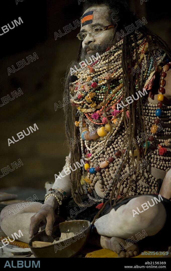 Lali Baba, a priest in Varanasi, waiting for worshipers that he will bless with ash (in the bowl at his feet). He is wearing necklaces given to him to worship Shiva.