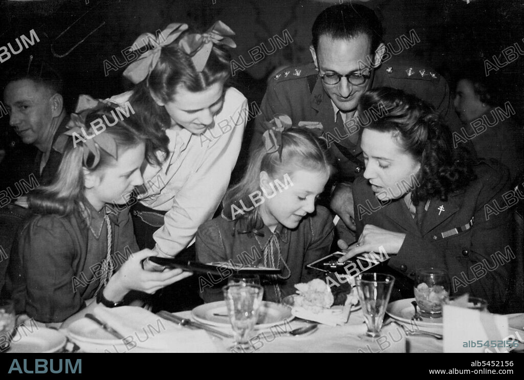 The Lady Of The Day - Mrs. Sansom, G.C. -- Mrs. Sansom, G.C. and Capt. Churchill with Mrs. Sansom's three daughters, Francoise, Lili and Marianne look at the decorations received at the Palace this morning, while at lunch to-day.
After going to the palace this morning, Tuesday, to receive the George Cross from the King, Mrs. Odette Sansom, M.B.E., and her former commanding officer, Capt. Peter Churchill, M.C., who was decorated with the D.S.O. at this morning's investiture, went to a luncheon at the Hungaria, Restaurant, London. November 19, 1946.
