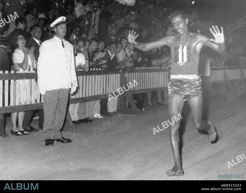 Orig. bildtext... After 42 km. of marathon the athlete of Etiopia, Abebe Bikila reached the first the finish line. He was tired but happy. Photo shows: the winner lifting the arms for joy. Orig. bildtext... OLYMPISK SLUTSPURT - Etiopiern Bikila Abebe går i mål som segrare i det gigantiska maratonloppet. Anm. Etiopisk maratonlöpare som barfota vann OS-guld i maraton 1960 Sommar-OS Vinnare Segrare Nummer elva Siffror Åskådare persons: ABEBE BIKILA sites: ETIOPIEN*;ROM;ITALIEN.
