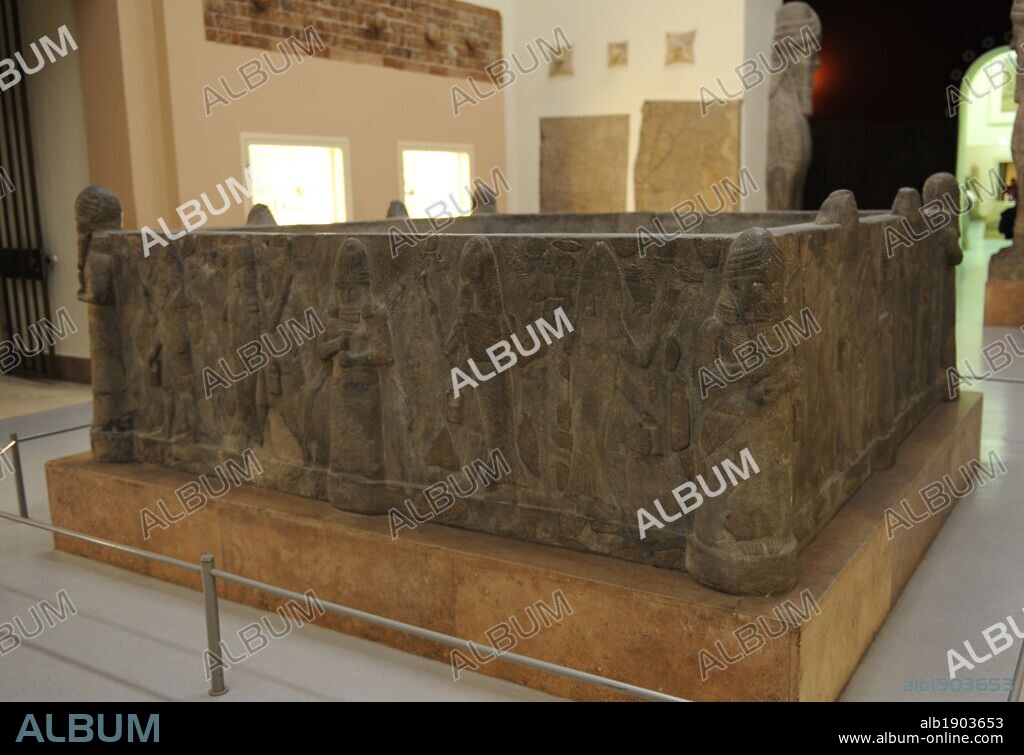 ARTE MESOPOTAMICO. PERIODO NEOASIRIO (912-612 a. C.). PISCINA o FUENTE DE AGUA, procedente de la ciudad de Assur (actual Irak). 704-681 a. C. Realizada en piedra basalto. Se localizó en uno de los patios del templo dedicado a la diosa Assur. Decorado con relieves que representan los rituales del agua. El agua fluye de arriba a abajo. Los sacerdotes vestidos de pez, con cántaross pequeños para realizar los rituales de purificación del agua de la figura central. Una inscripción cuneiforme invoca varias veces el nombre del rey SENAQUERIB (705-682 a. C.). Museo de Pérgamo (Isla de los Museos). Berlín. Alemania. Europa.
