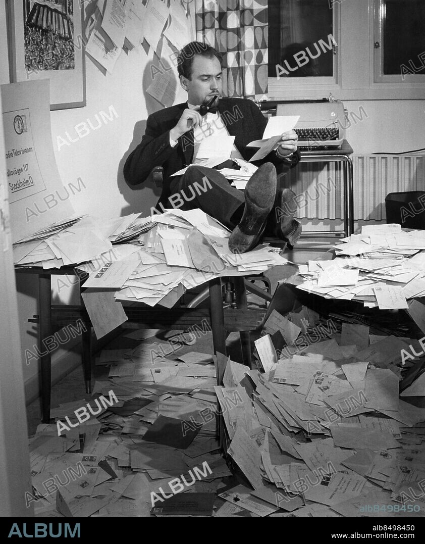 ARKIV 19580115.. Torbjörn Axelman, TV-producent och filmregissör, läser svarsbrev till programmet "Vet ni var?".. Foto: Ulf Stråhle / SVT / Kod: 5600. Bild publ. i RiR 6/58.. RiR 14247. Mapp: Axelman, Torbjörn. Pipor Fötterna på bordet Skosulor.