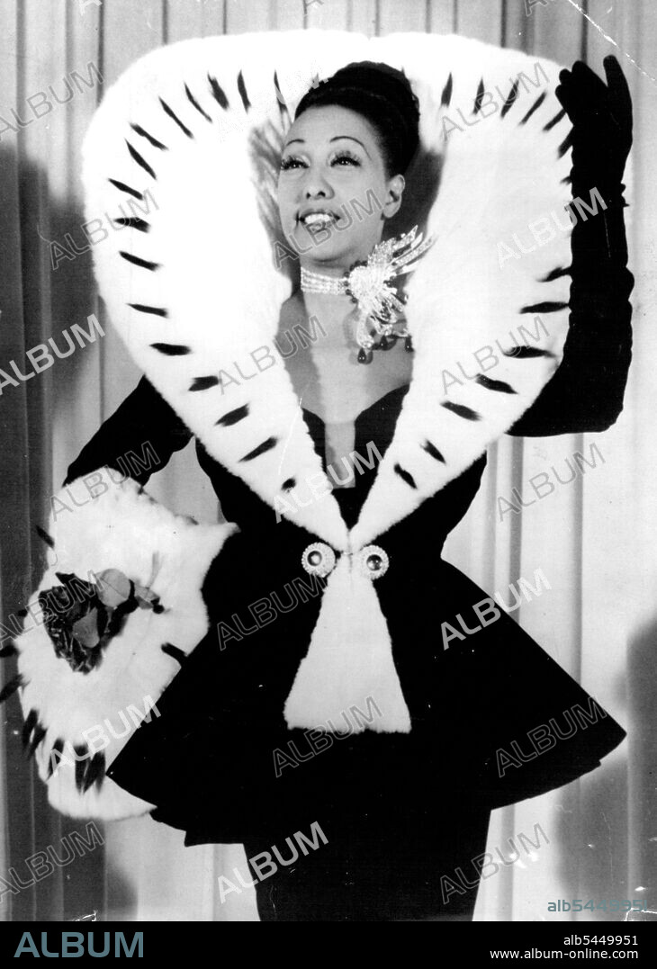 Josephine Baker In Sumptuous Balmain Dress For New York Appearances -- For one of her cabaret songs "Y A Pas trous moyens" She is to wear this dress of black velvets with a jacket bordered by Ermine, The skirt is straight, long, and trailing, with a waist of spangled moire. The Ensemble is accompanied by a muff of white, Ermine. Hair decorated with crosses of paradise roses Intermingled with red jewelry.
Jabaret star Josephine Baker will shortly leave Paris for New York where she has a heavy list of engagements at theatres, Cabarets, and in television. September 01, 1951.