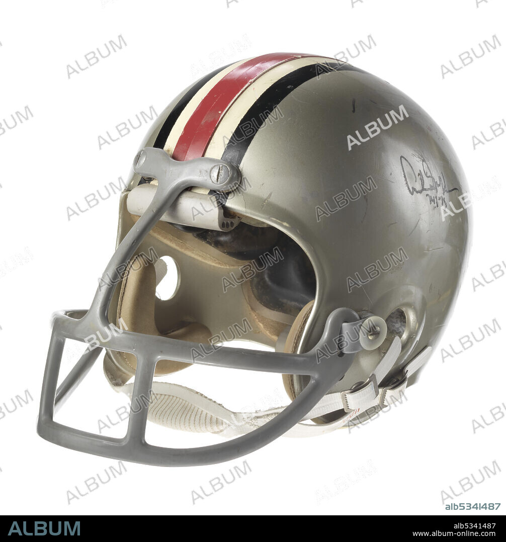 Archie Mason Griffin (born 1954) played as running back with the Ohio State Buckeyes American football team. The hard plastic helmet is gray with black, white, and red lines running vertically from the front to the back in the middle of the helmet. There are holes throughout the surface of the helmet. The inside of the helmet has thick black padding. Grey plastic-coated metal bars form a face mask. The face mask juts out severely from the front of the helmet. It has one vertical bar down the center and two curved horizontal bars with additional bars between the horizontal bars into three sections. There is a white leather chin strap, snapped onto both the left and right of the helmet The chin strap is attached with two buttons on each side. The chin strap is white with red type reading “RiddellR.” Additional illegible writing is on the bottom left of the strap. On the left center side of the helmet handwritten in black ink is “Archive Griffin / 74 / 75.” Centered on the back of the helmet is the number “45.” “Archie / [illegible]” is handwritten on the interior of the hat, by the left ear hole in a brown colored ink.