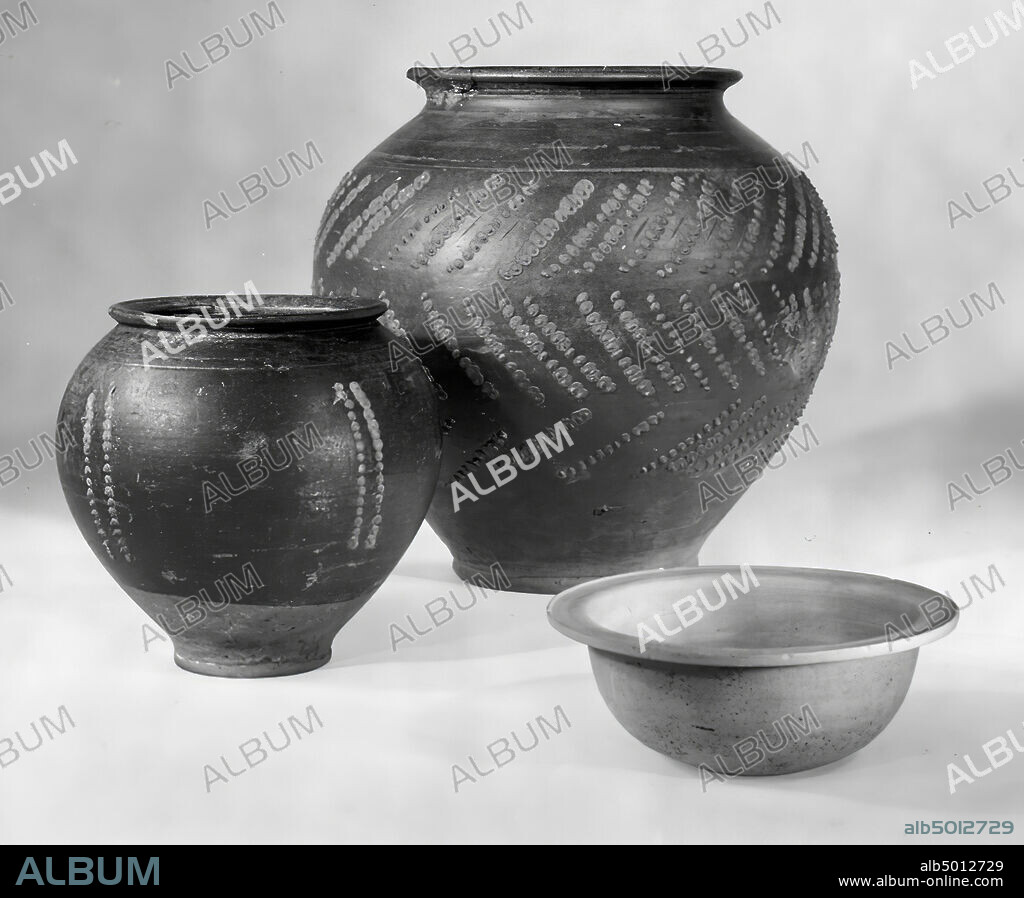 Roman pot of terra nigra (Hofheim type 114), convex shape with small, sloping edge. The belly decorated with imposed shields, between which are angled lines. Above the shields 2 horizontal lines. Glueing and complementing the edge, chip off the edge, crockery, pot, earthenware, terra nigra, h: 20.2 cm, diam: 19.8 cm, roman 35-45, Netherlands, Gelderland, Nijmegen, Nijmegen.