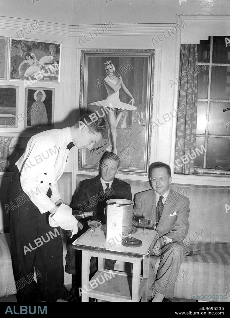 The interior of the Gargoyle Club in Dean Street, Soho. Wine waiter Rene Rudio serves to members of the club underneath paintings exhibited by the club's staff. 23rd March 1949.