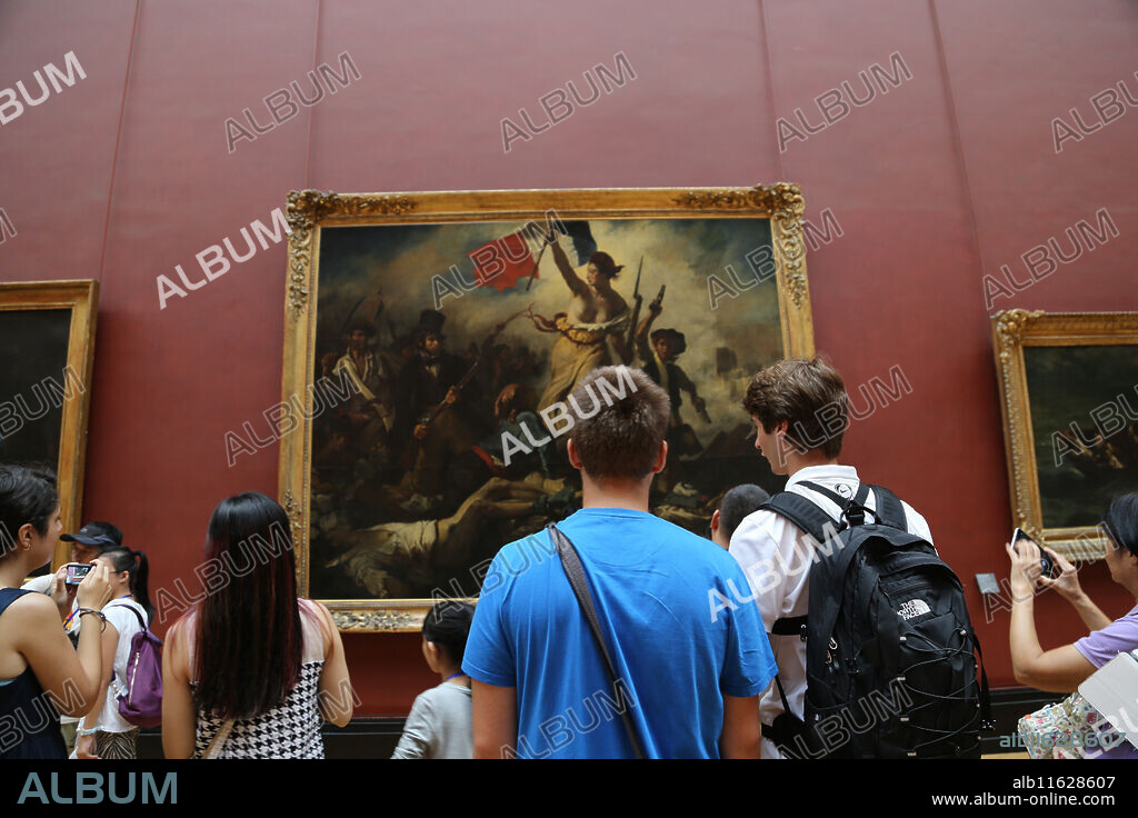 Tourist inside Louvre Museum.  Liberty leading the people, 1831. By Eugene Delacroix. Paris.