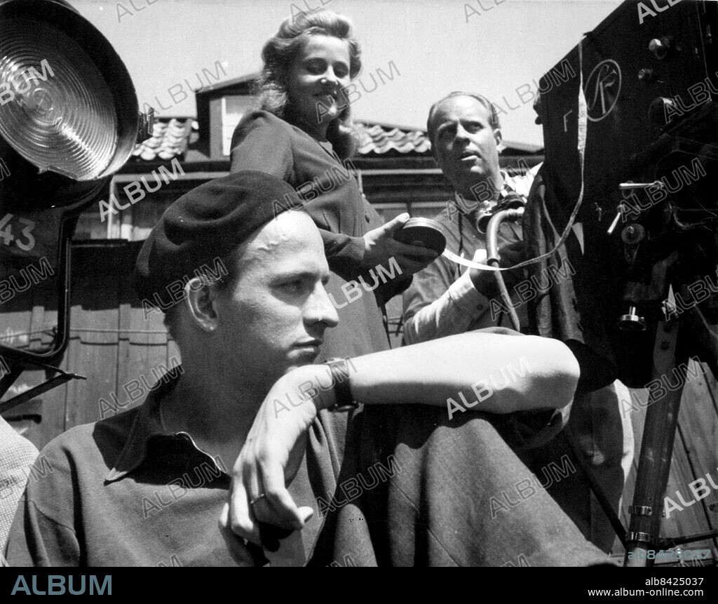 Arkivbild Regissör Ingmar Bergman. Filminspelning / filmen Drömmen om Nelly / närmast Ingmar Bergman. i basker och i bakgrunden Inga Landgré och fotografen Gösta Roosling. Film Drömmen om Nelly / Film Inspelning Kamera Kameror /. Bergman Ingmar regissör Scen 1945 /. Landgré Inga skådespelare Scen. (c) Sydsvenskan / IBL.