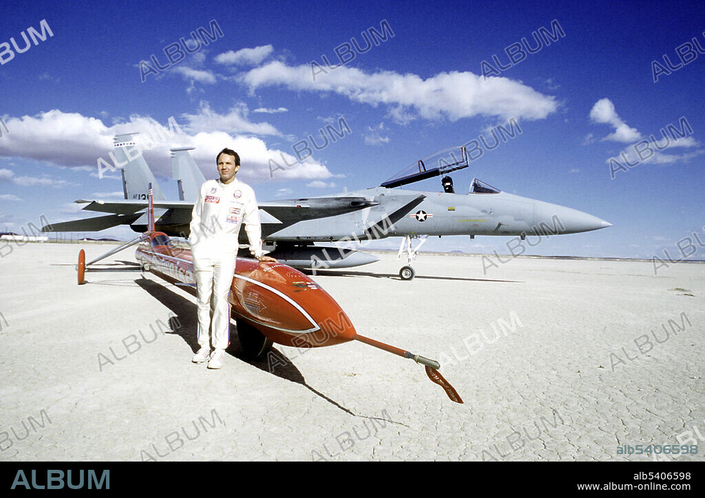 Stan Barrett, former Air Force medical technician, stands beside his rocket powered car. Born June 26, 1943, Barrett is a Hollywood stuntman, stunt coordinator and actor. On December 17, 1979, he attempted to break the Land Speed Record, and the sound barrier in the Budweiser Rocket rocket-powered three-wheel vehicle.  His calculated speed was 739.666 miles per hour, (Mach 1.01), which would have made Barrett the first man to break the sound barrier in a land vehicle. The attempt was surrounded by controversy and the speed was never officially recorded. Photographed at Rogers Dry Lake, Edwards Air Force Base, USA, June 1, 1980.