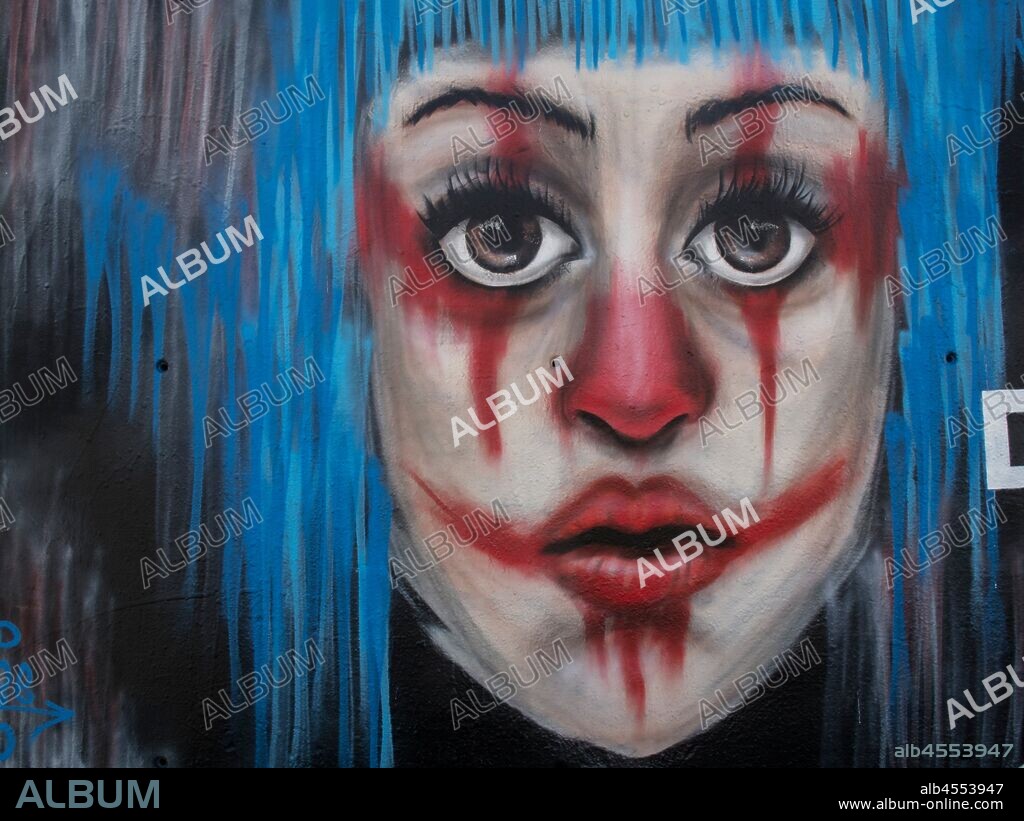 Pintura de rostro joven con pelo azul y cara pintada de payaso, graffiti mural, Plaza Tres Chimeneas, Poble Sec, distrito Sants Montjuit, Barcelona en 2016.