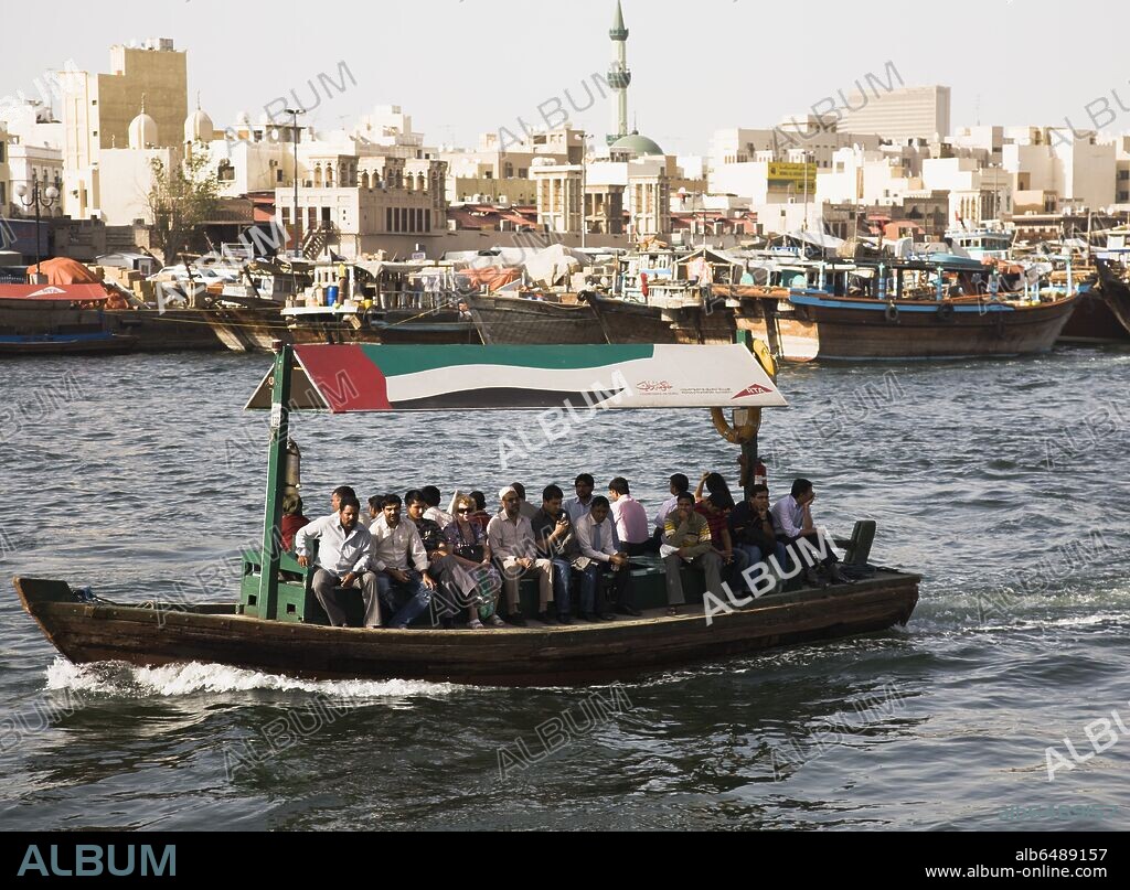 UAE , Dubai, Abra water taxi with commuters crossing the Creek Souk market behind.