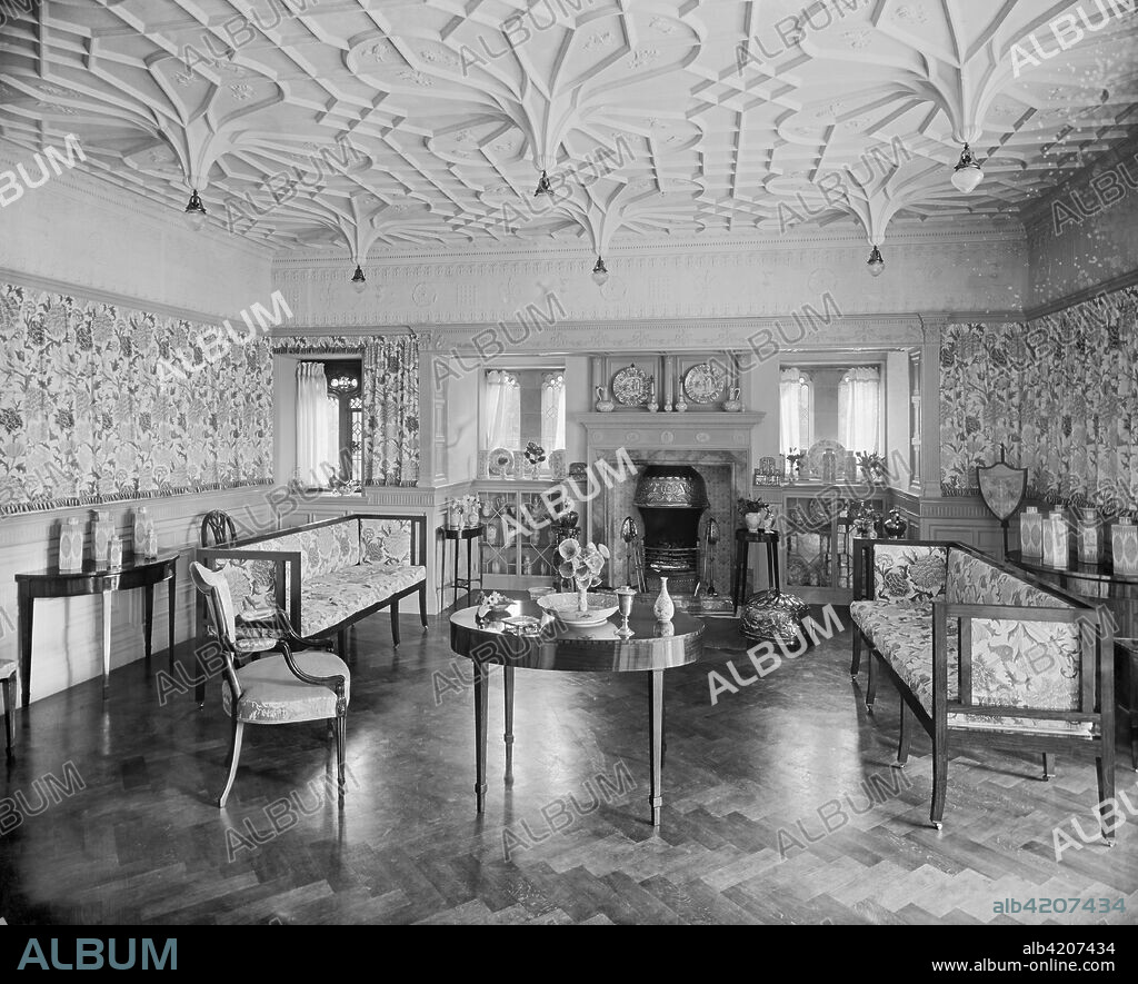 Victorian drawing room, Bidston Court, Birkenhead, Merseyside, 1894. View of the drawing room looking towards the windows and fireplace. Bidston Court was built in 1891 by the Liverpool architects Grayson & Ould. The drawing room is formally decorated, with Gothic windows, Tudor platerwork, Morris wallpaper and fabrics and Georgian-style furniture. The house was demolished in 1931 and rebuilt as 'Hillbark' in Roydon Park, Wirral, Merseyside.