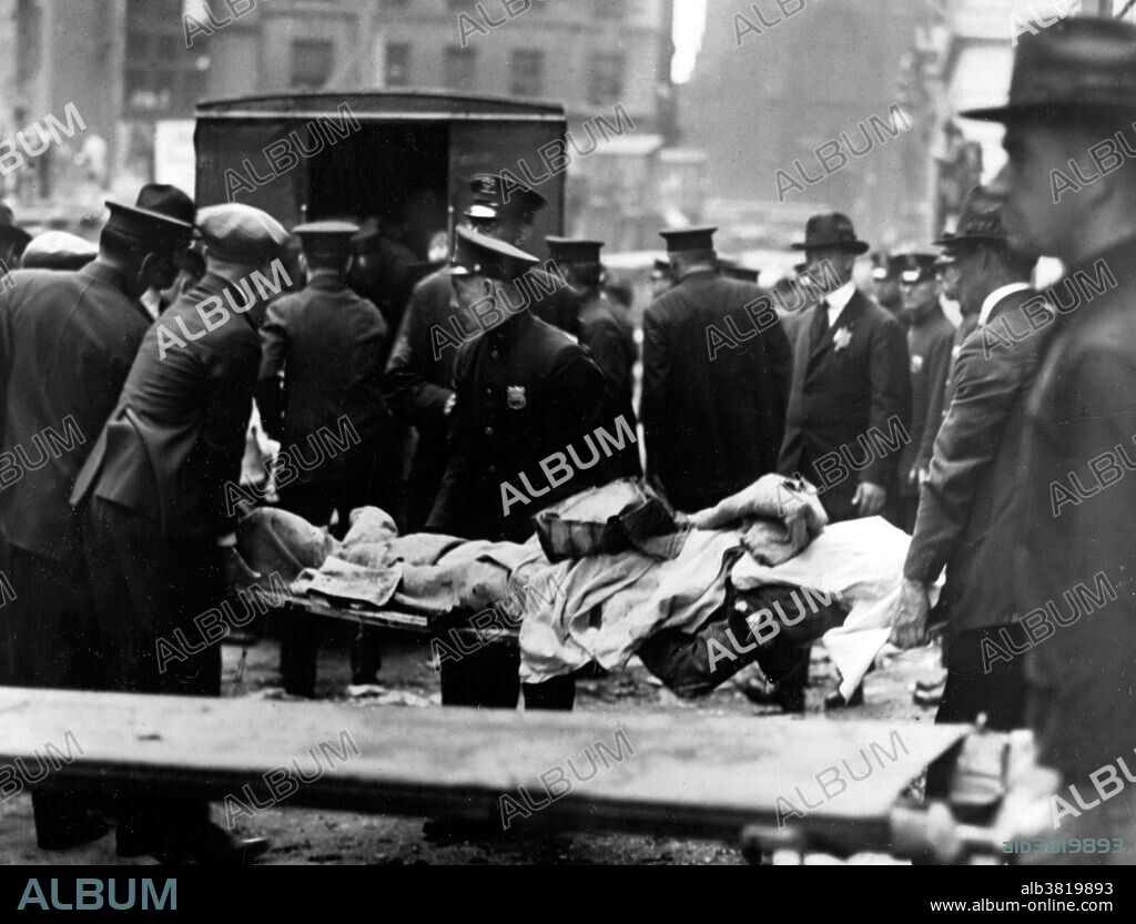 Entitled: "Removing bodies after Wall St. explosion." On September 16, 1920, a horse drawn wagon stopped across the street from the headquarters of the J.P. Morgan bank at 23 Wall Street. Inside the wagon, 100 lbs of dynamite with 500 lbs of cast-iron sash weights exploded in a timer-set detonation. The horse and wagon were blasted into small fragments, but the driver was believed to have left the vehicle and escaped. The 38 victims, most of whom died within moments of the blast, were mostly young people who worked as messengers, stenographers, clerks, and brokers. The bomb caused more than $2 million in property damage ($23,500,000 with inflation) and destroyed most of the interior spaces of the Morgan building. There were 143 seriously injured, and the total number of injured was in the hundreds. The bombing was never solved, although investigators and historians believe the Wall Street bombing was carried out by Italian anarchists, a group responsible for a series of bombings the previous year. Photographed by Underwood & Underwood, 1920.