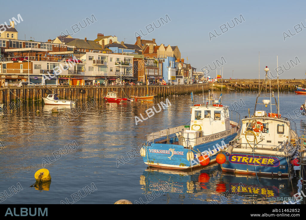 View of harbour boats and harbourside shops in Bridlington Harbour at sunset, Bridlington, East Yorkshire, England, United Kingdom, Europe.