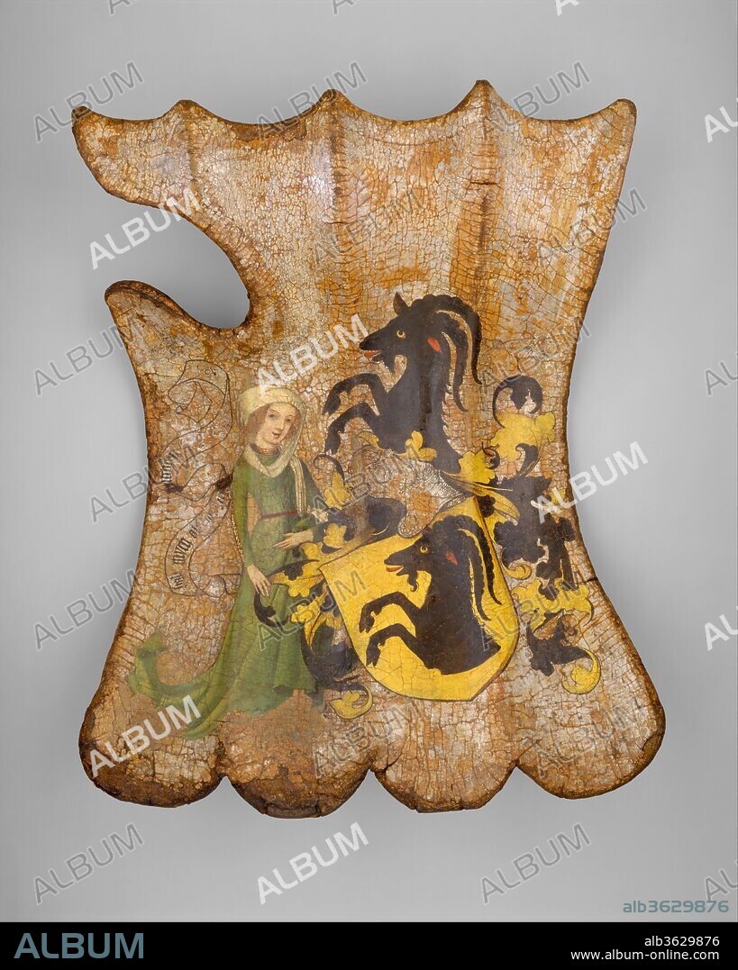 Shield for the Field or Tournament (Targe). Culture: German. Dimensions: H. 22 in. (55.88 cm); W. 16 in. (40.64 cm). Date: ca. 1450.
This shield is painted with a coat of arms belonging either to the Gottsmann family or to the related Türriegel family, both of Franconia. The female figure at the side holds a banderole inscribed in part with a motto in German: HAB MYCH ALS ICH BIN... (Take me as I am...). The decoration, with its brilliant colors on a silver-foil ground, is remarkably well preserved because it was hidden for centuries beneath layers of later paint. On the leather-lined back of the shield are traces of a painted figure of Saint Christopher, whose image was thought to protect against sudden death.