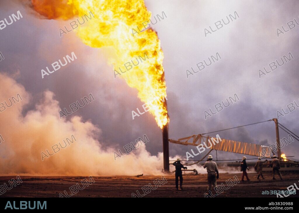 Kuwait City, Kuwait; March 1991. American oil rig workers contracted by the Kuwaiti government attempt to plug and stop oil wells burning out of control in the Al-Ahmadi oil fields located on the outskirts of Kuwait City. The oil fields were set on fire by retreating Iraqi troops hoping to create some cover from American airplanes strafing their positions. The fires and smoke caused one of the greatest environmental disasters of modern times. Nearly 800 oil wells were set ablaze by the retreating Iraqi army and the fires were not fully extinguished until November 6, 1991, eight months after the end of the war. The fires consumed an estimated six million barrels of oil daily. Their immediate consequence was a dramatic decrease in air quality, causing respiratory problems for many Kuwaitis. The sabotage of the oil wells also impacted the desert environment, which has a limited natural cleansing ability. Un-ignited oil from the wells formed about 300 oil lakes that contaminated around 40 million tons of sand and earth.