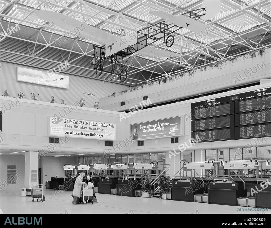 Birmingham Airport, Birmingham Maglev, Elmdon, Birmingham, Bickenhill, Solihull, 23/01/1985. The interior of the central well in the new terminal building at Birmingham International Airport after its opening, showing passengers in front of a row of check-in desks. Construction of a new terminal building and piers, extensions to runways, and a new Maglev system at Birmingham Airport began in May 1981. The new terminal building was located on the opposite side of the site to the existing terminal at Elmdon. It was built using a structural steel frame around a central well, with precast floor and roof units, and was clad in glassfibre reinforced concrete. The three-storey building had a floor area of 16,000 sq metres. It was later known as Terminal 1.