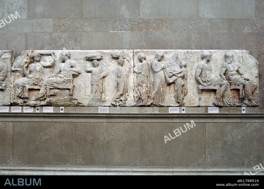 The Parthenon frieze. East side. 447-432BC. Greek Classical period. Part of the central section of the east frieze. Zeus and Hera seated next to a standing man receiving the folded peplos from a young boy. British Museum. London. England. United Kingdom.