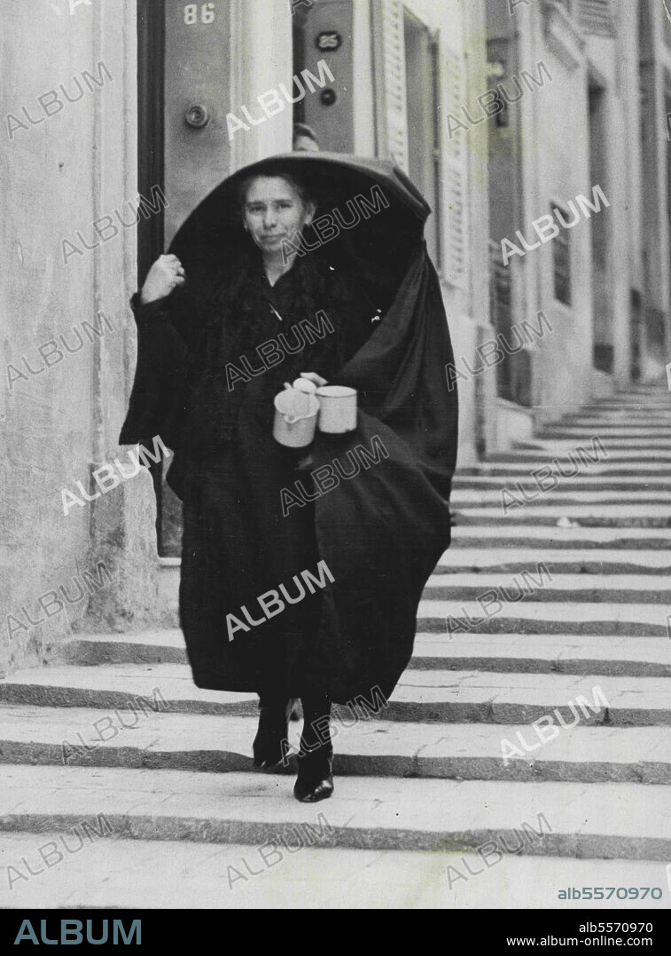 In Old World Valitta -- Maltese Woman wearing the Faldetta or "Hood of Shame". The "Hood of Shame" is still worn by Maltese Women. The headdress cape known as the Faldetta has a curious appearance and history relates the women were ordered to wear them for a 100 years as a penanee for their lack of charity at the time when Napoleon's troops were stationed in Malta in 1798. Although the Century has long since past the picturesque fashion has not lapped. January 04, 1936. (Photo by Fox).