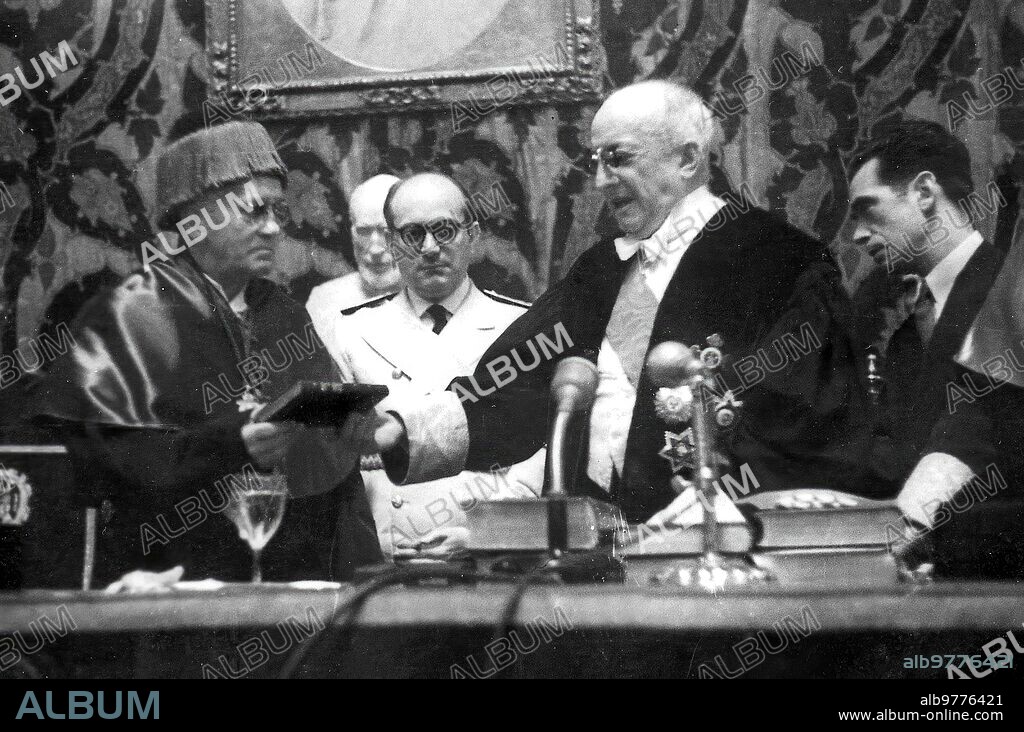 Madrid, 12/06/1948. Sir Alexander Fleming, con el birrete laureado, en el momento de ser nombrado Doctor  Honoris Causa y de recibir la Gran Cruz de Alfonso X El Sabio de manos del ministro de Educación nacional, D. José Ibáñez Martín y del rector de la Universidad Central de Madrid, D. Pío Zabala.