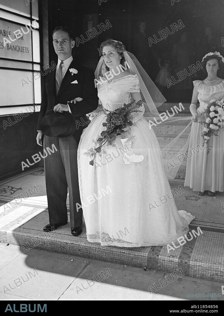 BOY , 16 , MADE BRIDE'S CRINOLINE. From a design chosen by the bright, 16-year-old Douglas Darnell of Kilburn (London) made the crinoline wedding dress in which Miss Patricia Bones, aged 18, of Barking, was married to Mr.L.Johnson of Grays (Essex) at Caxton Hall register office, London,. The off- the- shoulder gown studded with mother- of- pearl sequins was made entirely by the boy. PICTURE SHOWS:- The bride, in crinoline dress and carrying a ' lucky boot ', leaving Caxton Hall with the bridegroom after the wedding. July 8 1949.