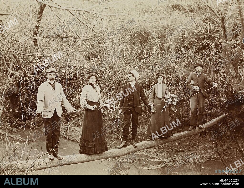 Digital Photograph - Partington Family Crossing the Plenty River on Log Footbridge, Greensborough, Victoria, circa 1885, Sepia image of five members of the Partington Family crossing a 'log bridge' over the Plenty River. The family lived at 'Willis Vale' and made the bridge in order to travel to neighbouring properties. Here they are on their way to the old Mitchell place to have a picnic. The man on the right is William James Partington. The image was originally processed by H.W Roisien of Richmond.