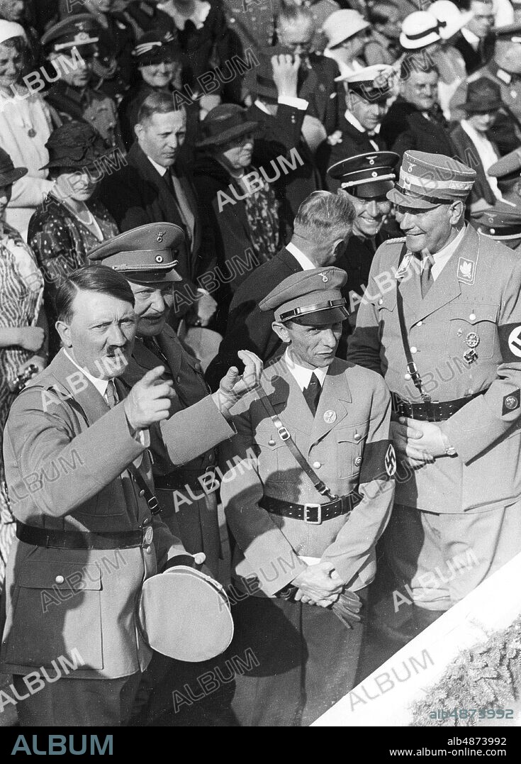 GERMANY BERLIN 1934-05-01. Orig. caption ... 1 MAY 1934, THE GERMAN PEOPLE'S NATIONAL HOLIDAY AT WORK. 46390 During the giant proclamation on the Tempelhofer Feld: Der Führer mit den Reichsministern Goering und Dr. Goebbels on the grandstand. Photo: Robert Sennecke / AB Text & Bilder / SVT / Code: 5600 Folder: 1 May in Berlin 1933-39 Germany 2694 A2 Swastika Point persons: ADOLF HITLER; JOSEPH GOEBBELS; HERMANN GÖRING sites: BERLIN; GERMANY.