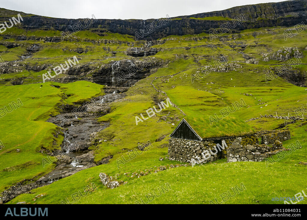 Grasstop roof house before a waterfall, Saksun, Streymoy, Faroe Islands, Denmark, Europe.