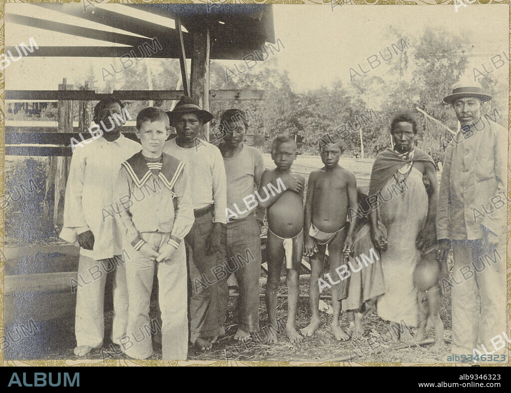 Anton with Arowaks and Maroons, The Dutch boy Anton standing posing in front of a group of Surinamese Arowaks and Maroons. Part of the photo album Souvenir de Voyage (part 2), about the life of the Doijer family in and around the plantation Ma Retraite in Suriname in the years 1906-1913., Hendrik Doijer (attributed to), Suriname, 1906 - 1913, photographic support, gelatin silver print, height 121 mm × width 169 mm.