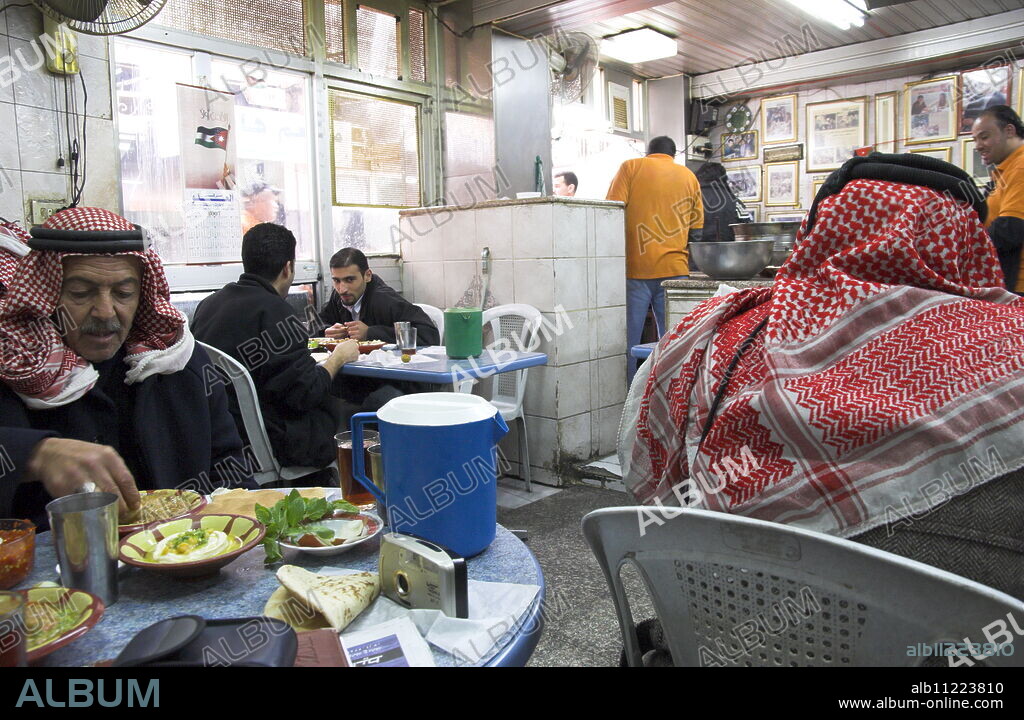 Men in keffiyeh eating traditional humus in Hashem restaurant, downtown area, Amman, Jordan, Middle East.
