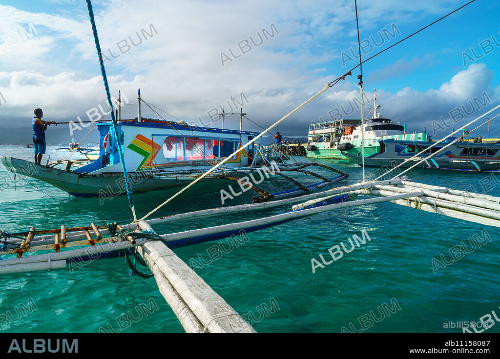 Bangkas (outrigger canoes) and the old ferry compete for landing space at the harbour, Borocay Island, Philippines, Southeast Asia, Asia.