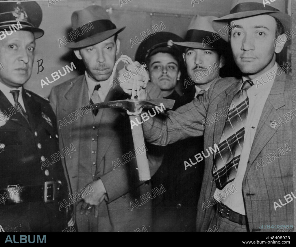 Mexican policeman holds pickaxe used by slayer of Leon Trotsky, exiled Russian leader whose head was broken open August 20 at his closely guarded home near Mexico City. Picture was made after police subdued Trotsky's assailant. August 21, 1940.