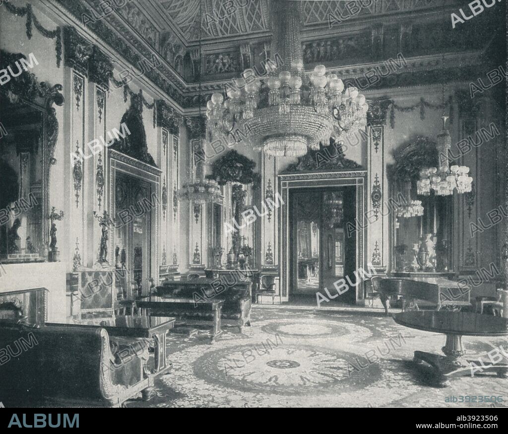 'The White Drawing-Room at Buckingham Palace', c1899, (1901). John Nash (1752-1835) reserved one of his most original ceiling designs for the White Drawing Room, ebony-veneered cabinets with gilt-bronze mounts are built into the wall beneath tall mirrors, one of them contains a concealed door. From V.R.I., Her Life and Empire, by The Marquis of Lorne, K.T. [Harmsworth Bros Ltd., London, 1901].