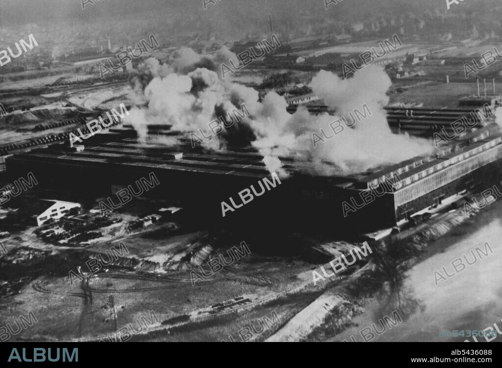 R.A.F. Daylight Raid on Poissy Factory, a low altitude daylight on the Matford factory at Poissy, which has been producing twenty lorries a day for the German Army. A clear view of the lines of lorries seen in this photograph (left) while smoke from bombs bursting inside the factory drifts over the area. June 30, 1942. (Photo by British Official Photograph).