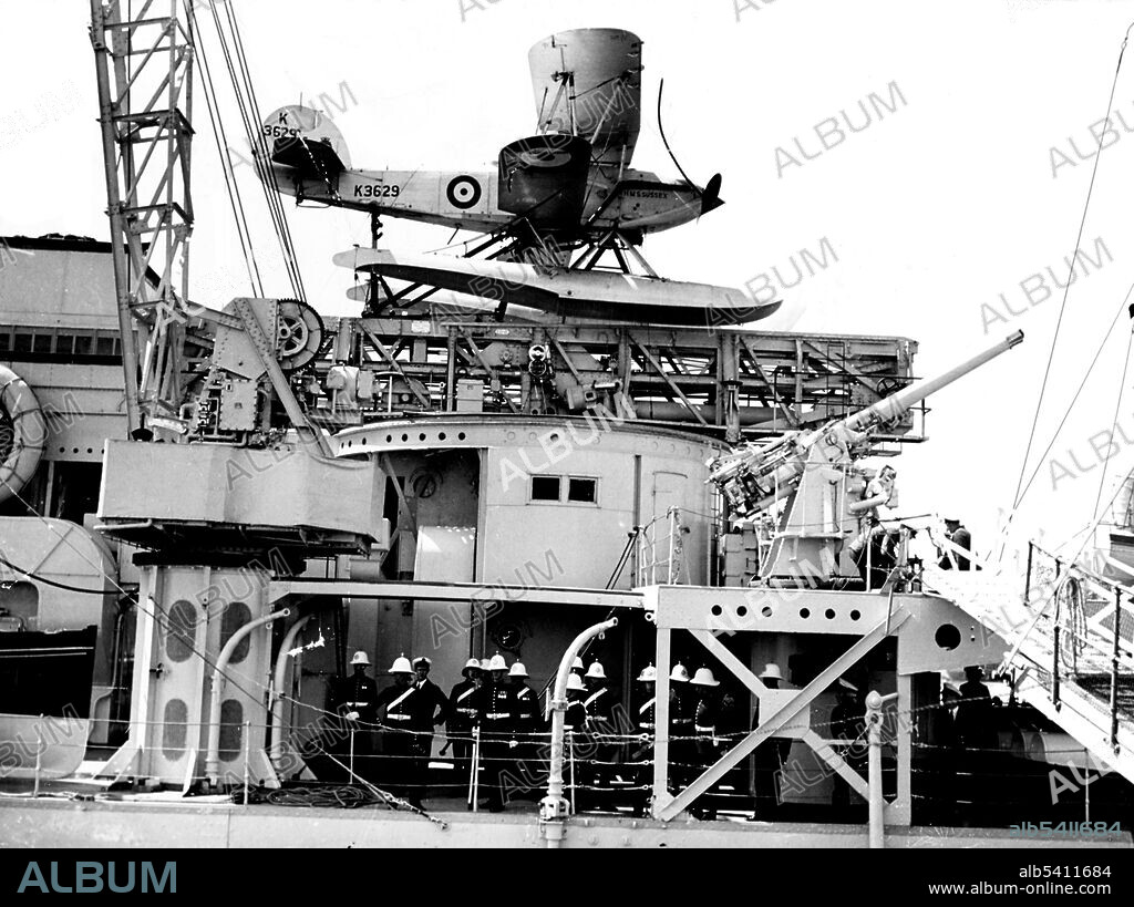 HMS Sussex was one of the London sub-class of the County-class heavy cruisers in the Royal Navy. View amidships, taken during the 1930s, showing aircraft crane, catapult, 4"/40 anti-aircraft gun and Hawker Osprey plane. The Hawker Osprey was the navalized carrier-borne version of the Hart, performing in the fighter and reconnaissance roles. Note honor guard of Royal Marines in tropical dress uniforms. (cropped and cleaned).