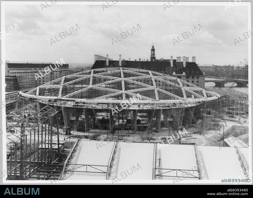 FESTIVAL OF BRITAIN OFFICE. Festival of Britain, South Bank Exhibition, Dome of Discovery, Chicheley Street, South Bank, Lambeth, Greater London Authority, 10-07-1950. The partially constructed Dome of Discovery on the South Bank, with County Hall behind, and the roof of the Transport Pavilion in the foreground. The original caption reads: "Progress picture of construction work on 1951 Exhibition, South Bank, London. View of Dome of Discovery showing aluminium alloy arches to support aluminium roof. Part of Transport Pavilion is in foreground." The Dome of Discovery was designed by Ralph Tubbs. The building was a temporary structure using reinforced concrete and aluminium. At the time it was the largest aluminium structure ever erected, and was also the biggest dome in the world. It measured 365 ft in diameter, and was alsmost 100 ft high.