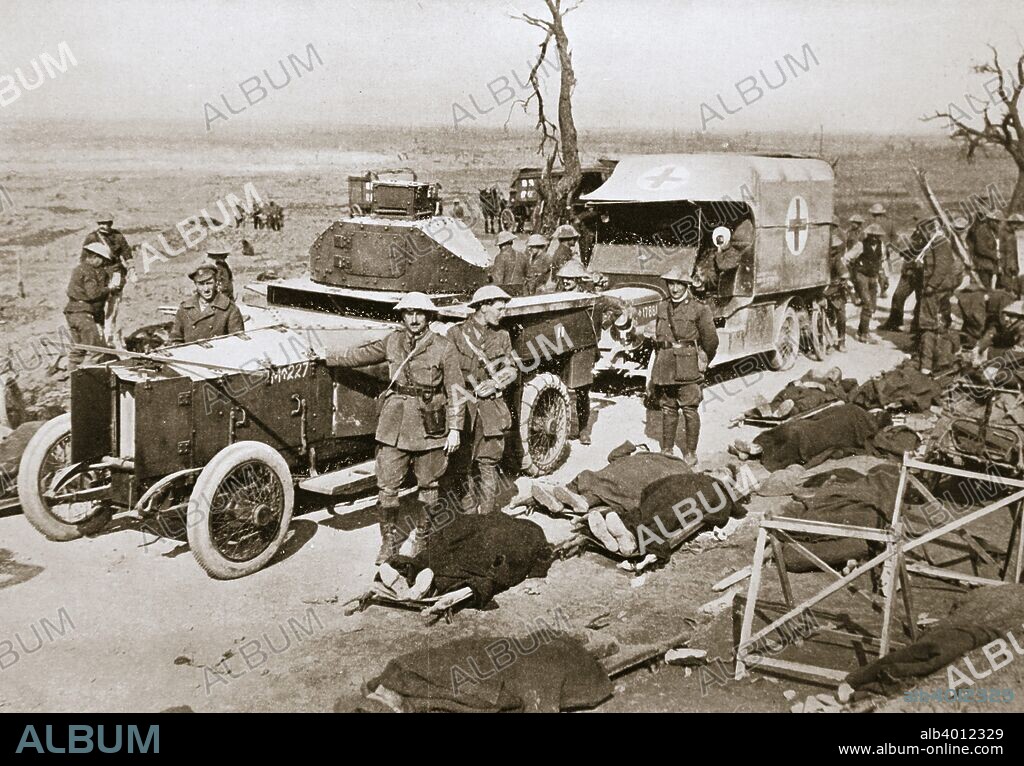 British armoured car, near Guillemont, France, Somme campaign, World War I, 1916. Stretcher cases are lying beside the road and an ambulance stands behind the armoured car.