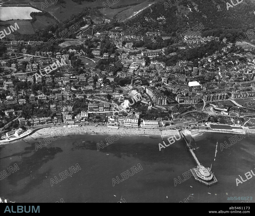 Isle of Wight From the Air:Ventnor, Isle of Wight.View of Ventnor, the beach and the pier; Ventnor has a population of 6,000. It is situated in the Undercliff district at the foot of the St. Boniface down, which is 787 feet high. In the early 19th century it was a small fishing hamlet, but now it expends along the shore for two miles. Ventnor, built on a succession of terraces, i6 regarded as one of the best resorts in England for consumptives and contains several hospitals and convalescent homes. November 4, 1954. (Photo by Camera Press).