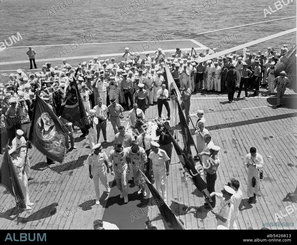 Gemini IV crew arrives on the USS Wasp, June 7, 1965. Astronauts Edward H. White II and James A. McDivitt on the flight deck of the aircraft carrier USS Wasp after their record-breaking 62-revolution, 97-hour and 56-minute flight which ended in the Atlantic Ocean about 400 miles east of Cape Kennedy at 12:12 p.m. (Eastern Time). Here they are shown being welcomed by members of the crew and NASA officials. White and McDivitt (center) walk on the red carpet flanked by Capt. J.W. Conger (left), commander of the ship; and Rear Admiral W.M. McCormick, commander, Carrier Division 14, Atlantic Fleet. NASA's Gemini IV flight landed about 48 miles short of the aircraft carrier.