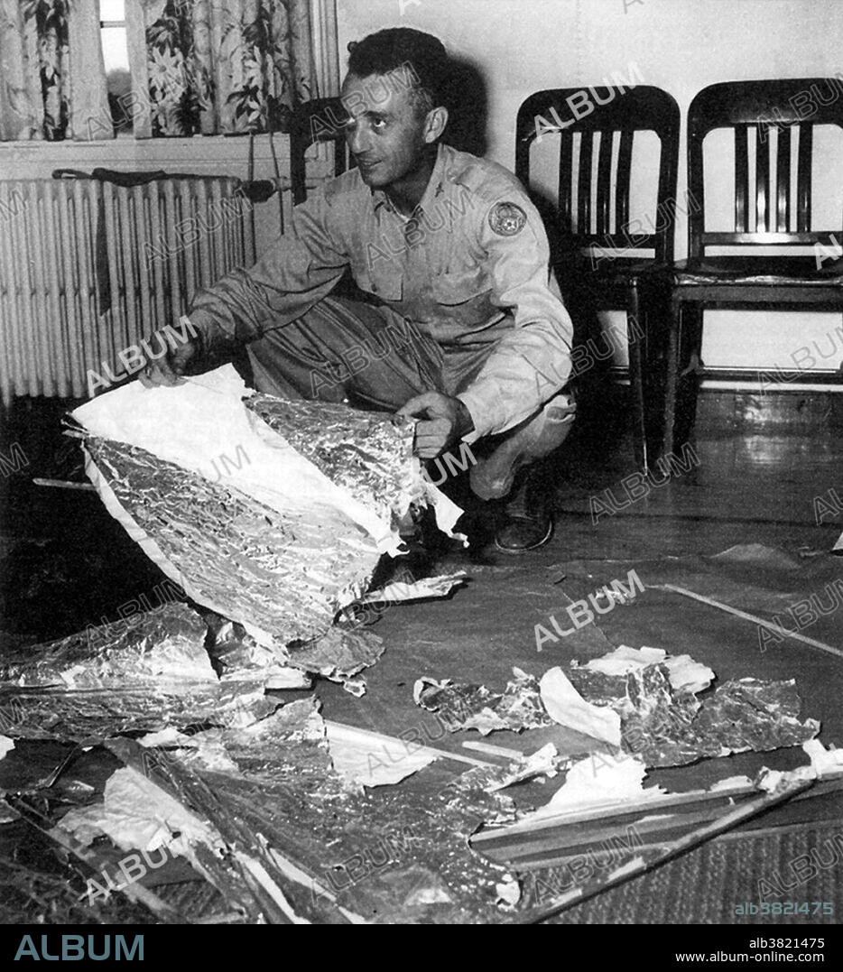 Editorial use only . Major Jesse Marcel at Fort Worth, Texas with balloon debris. This photo of Marcel with weather balloon material was widely published, but supposedly he would later admit the material he picked up at Brazel's ranch was not part of any kind of weather balloon or experimental balloon. In 1947, a crash of a military Air Force surveillance balloon at a ranch near Roswell, New Mexico gave rise to claims alleging the crash was of an extra-terrestrial spaceship. After an initial spike of interest, the military reported that the crash was merely of a conventional weather balloon. In the 1970s there were a variety of increasingly elaborate conspiracy theories claiming that one or more alien spacecraft had crash-landed and that the extra-terrestrial occupants had been recovered by the military who then engaged in a cover-up. The Roswell incident continues to be of interest in popular media, and conspiracy theories surrounding the event persist.