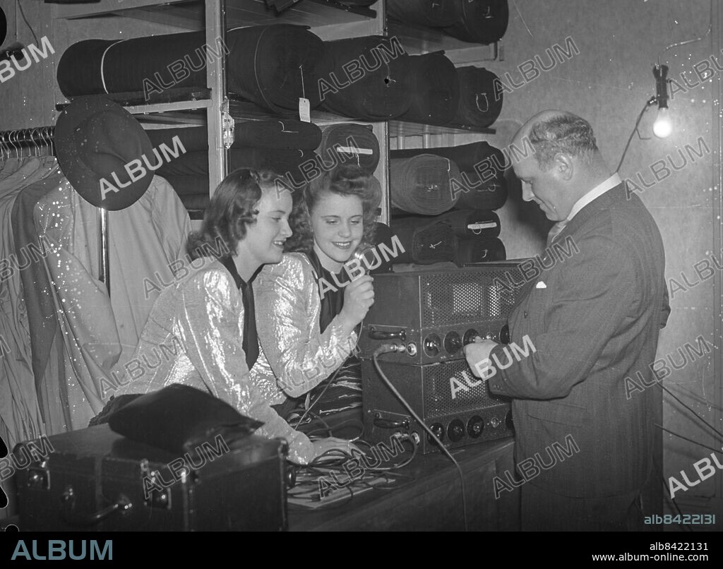 GÖTEBORG 1943-04-11.. Annorlunda ställe. Vi finner stuvar av tyg, tygbalar i hyllor och en hatt. Två kvinnor prövar en förstärkaranläggning - troligen har det med GT:s arrangemang från Pettersson & Katz balkong vid Kungstorget att göra. GT har ett arrangemang på torget med tusentals åskådare - GT:s Norgekabarét - . *** Local Caption *** GT Låda 1943-mars-april-maj-jun-jul-aug- Foto: Kamerareportage / TT / Kod: 2524.