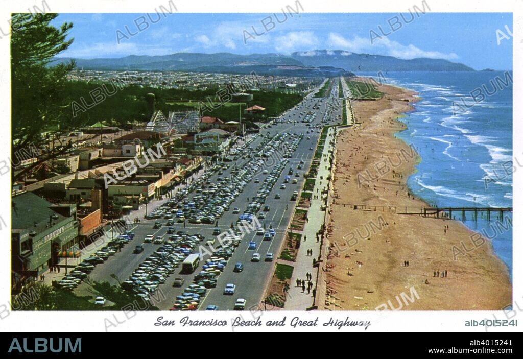 San Francisco Beach and Great Highway, California, USA, 1957. Vintage postcard showing a bird's eye view of the San Francisco Beach and Great Highway looking south. Cars line the parking lots, people walk along the beach and mountains are seen in the distance. Shops and businesses line the street opposite the ocean.