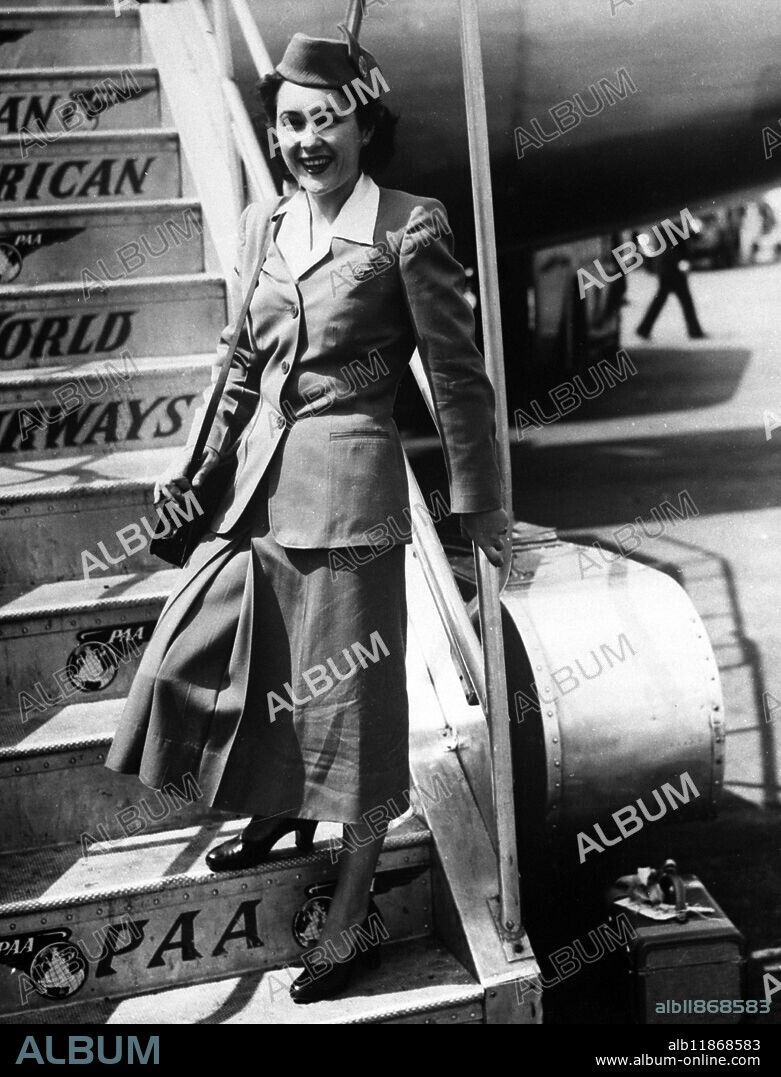 Highly honoured girl on a maiden trip is 23-year-old Stewardess Priscilla Nolin , seen here on the steps of a Pan-American Stratocruiser at London Airport. Priscilla , who is from Haverhill, Massachusetts , came top of her class at the company's stewardess school in New York and , as a reward , was assigned to the Stratocruiser for her first trans-Atlantic air trip. 27 July 1949.