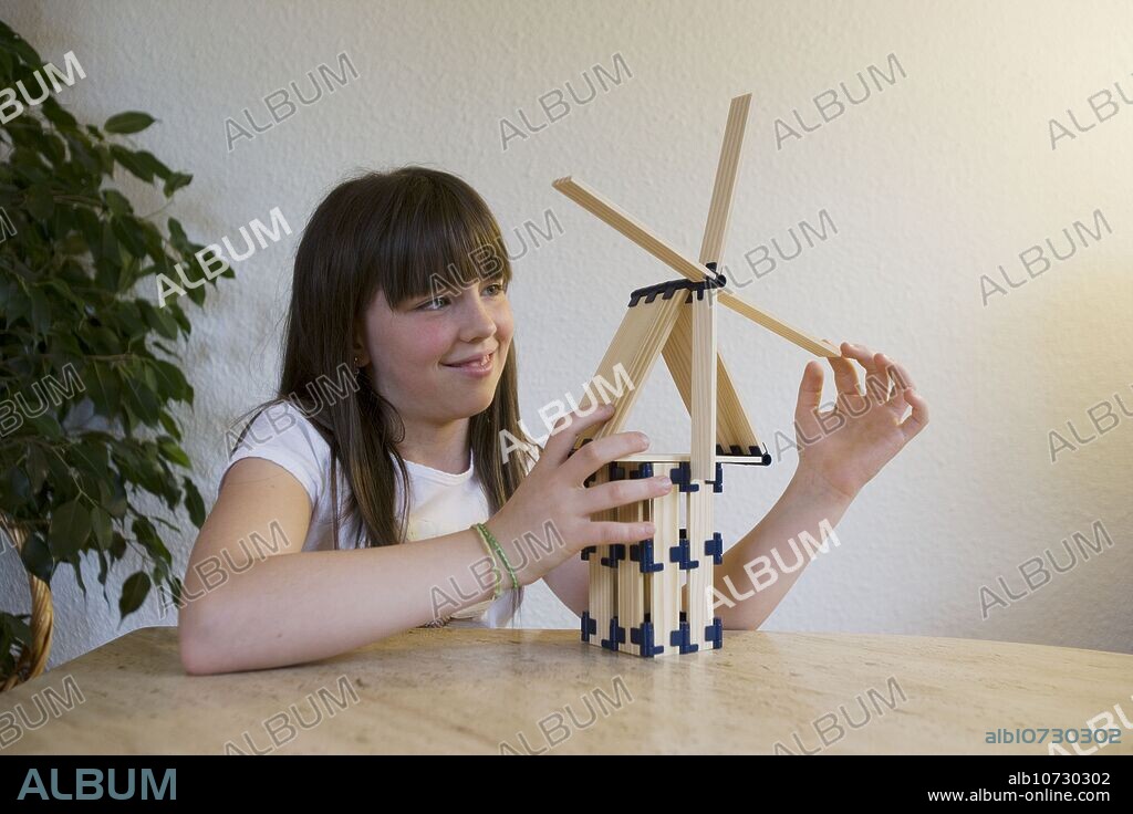 Girl playing with wooden windmill toy.