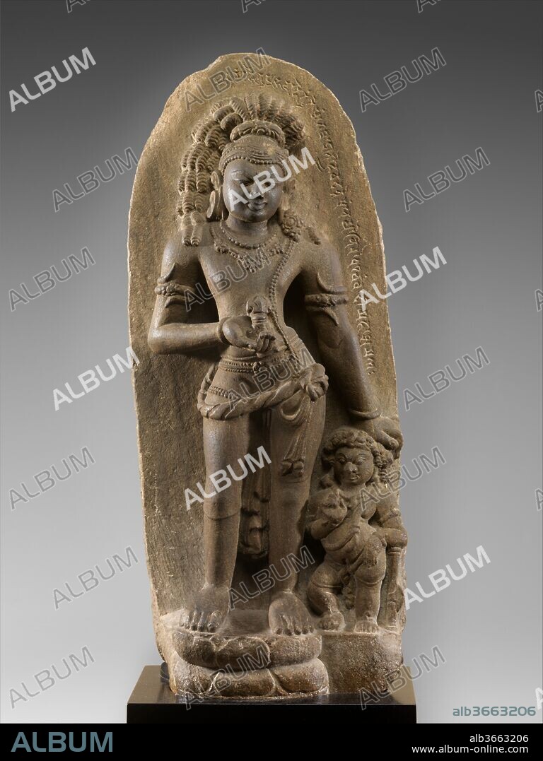 Vajrapani, the Thunderbolt-bearing Bodhisattva. Culture: Eastern India (Bihar, probably Nalanda). Dimensions: H. 30 7/8 in. (78.4 cm); W. 23 13/16 in. (60.5 cm); D. 6 in. (15.2 cm). Date: 7th-early 8th century.
This is a rare representation of the Buddhist savior Vajrapani from the seventh century or soon after. Vajrapani, the "holder of a thunderbolt" (vajra), shares his origins with the Vedic deity Indra, god of storms. Early in Buddhist iconography, the thunderbolt scepter assumed an independent meaning associated with clarity of pure thought leading to enlightenment. Vajrapani stands flexed holding the vajra in his raised hand, the other resting on the dwarf attendant with a club-axe who seemingly mimics his gestures. Vajrapani has long, unkempt dreadlocks that imply an esoteric aspect to his personality, evocative of Shiva; the large, asymmetrical ear ornaments only strengthen this association, as does the gana-type dwarf guardian. He is best understood as a purusa, a personification of Vajrapani's "weapon," a visualization practice very much in vogue in this period in Hindu iconography, especially in Kashmir. A Sanskrit inscription in proto-Bengali script extends down one side of the stele.